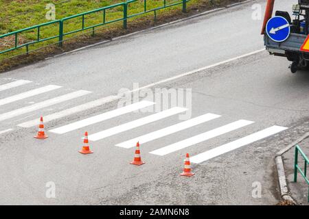 The road service updates the pedestrian crossing on the highway with paint. Prohibiting chips before a pedestrian crossing Stock Photo