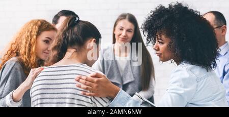 Support group patients comforting woman at therapy session Stock Photo