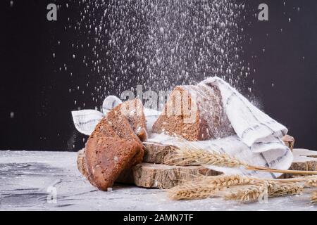 Triangular bread under falling flour . Stock Photo
