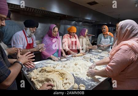 Sikh men & women of various ages make roti breads in a langar, free communal kitchen, in the basement of a temple in Richmond Hill, Queens, New York C. Stock Photo