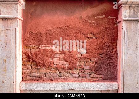 Red bricks with ochre paint peeling off wall at Venice, Italy. Stock Photo
