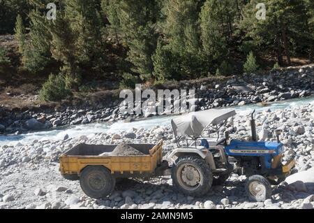 Construction site dumper Dump truck Lorry with heavy load capacity tipping earth rock sands and boulders from riverbank foundation for excavator in re Stock Photo