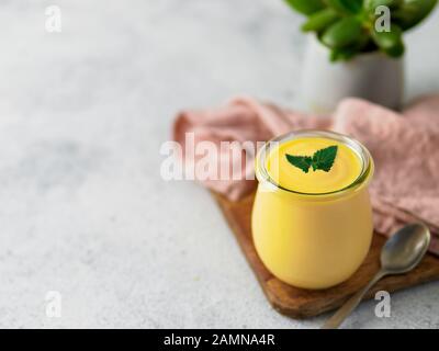 Yellow mango lassi on gray background. Indian mango yogurt drink with copy space left. Stock Photo