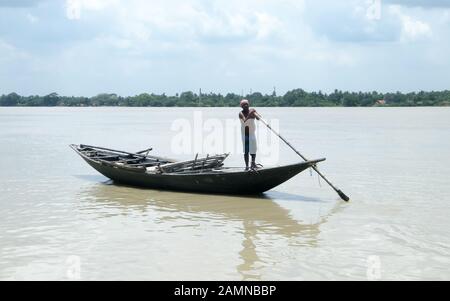 Traditional boatman (ferry people Majhi) rowing boat (called Nauka) on river Ganges (Ganga). Rural Indian travel tourism and water transportation them Stock Photo