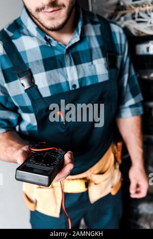 Cropped view of repairman holding multimeter sensors on disassembled ...