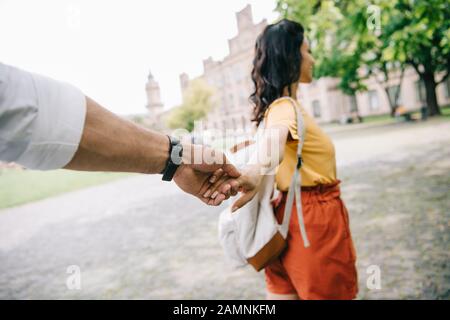 cropped view of man holding hands with woman walking near university Stock Photo