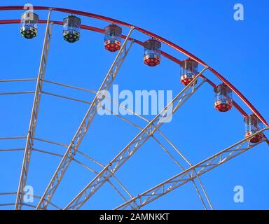 Horizontal image with close-up of section of colorful bright red, green and white panoramic or observation wheel with few empty cabins. No people. Cle Stock Photo
