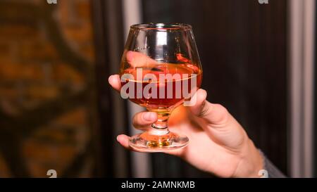 Close-up of persons hand holding glass with whiskey or bourbon. Concept of nightlife Stock Photo