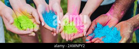 panoramic shot of multicultural friends holding colorful holi paints in hands Stock Photo