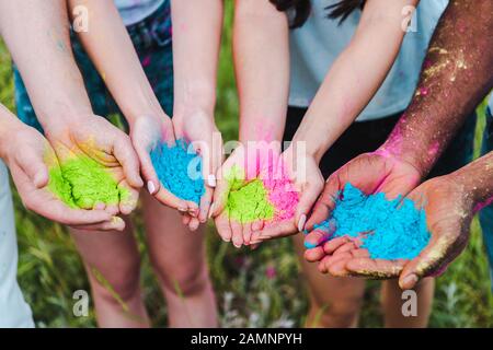 cropped view of multicultural friends holding colorful holi paints in hands Stock Photo