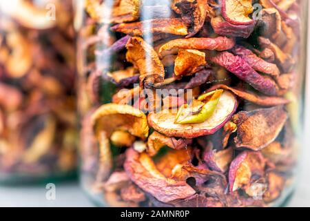 Dehydrated dry orange red colorful homemade pieces apple fruit slices stored in many glass jars macro closeup showing texture Stock Photo