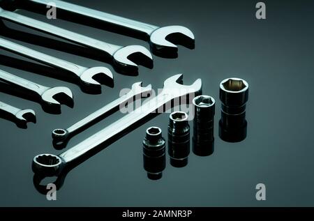 Set of chrome wrenches or spanners and hexagon socket on dark table in workshop. Chrome vanadium spanner wrench. Shiny silver wrenches and socket. Stock Photo