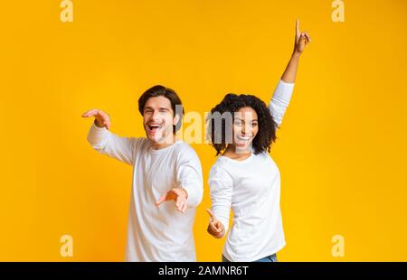 Carefree guy and girl dancing back to back, having fun together Stock Photo