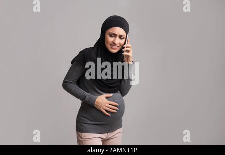 Pregnant arabic woman suffering from abdominal pain and calling to doctor Stock Photo