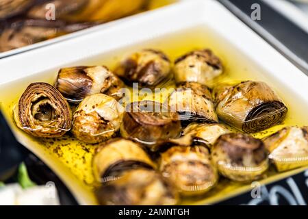 Marinated grilled artichokes vegetables in olive oil in market shop grocery display in Florence Italy macro closeup Stock Photo