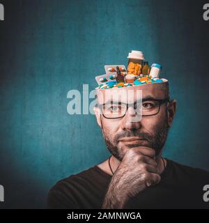 Portrait of man with glasses and hand on chin. Thoughtful look. Abstract image, head full of medicines. Concept linked to the ethical and excessive us Stock Photo