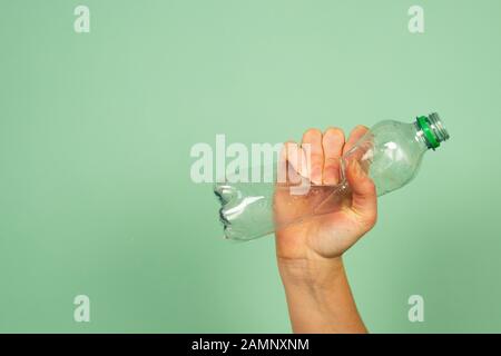 Woman's hand holding smashed empty plastic water bottle not used, concept of recycling Stock Photo