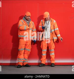 Construction Workers. A pair of brightly dressed manual workers  taking a cigarette break from their work. Stock Photo