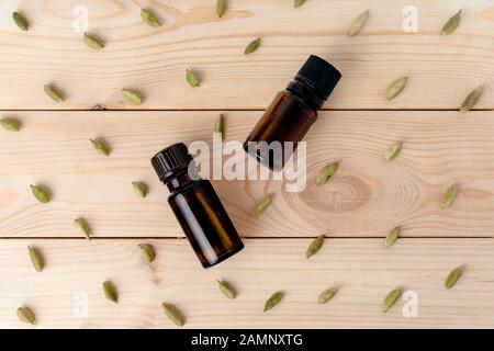 two glass bottles with cardamom on a light wooden background. Flat lay. Stock Photo