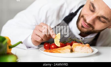 Chef Plating Roasted Fish Dish Decorating Food In Restaurant Kitchen Stock Photo
