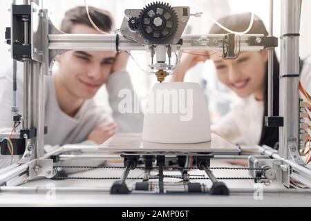 Engineering students using an innovative 3D printer in the university lab, they are printing a prototype together, creativity and education concept Stock Photo