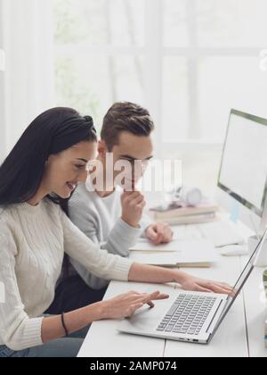 Young academic students at the library, they are studying together and reading a book Stock Photo