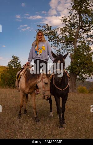 A teenage girl stands in stirrups on two horses at the same time.