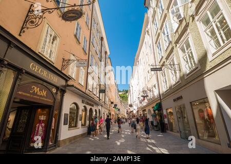 Salzburg, Austria - July 23, 2019: Famous busy pedestrian shopping  street Getreidegasse with vintage  wrought iron guild signs in the old town. Stock Photo