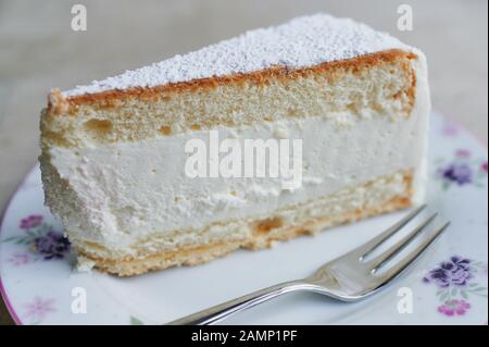 close up of cream-cheesecake on a plate beside is lying a fork Stock Photo