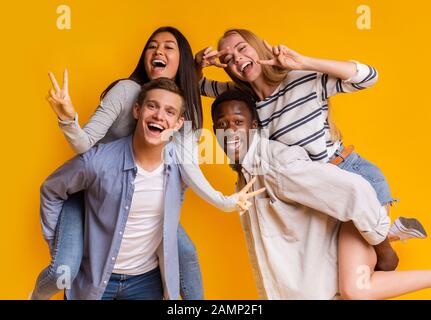 Two international teen couples having fun over yellow background Stock Photo