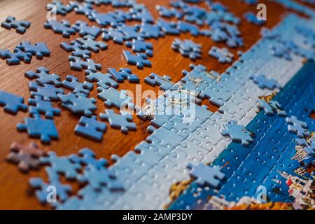 Partially solved jigsaw puzzle with scattered puzzle pieces on the table Stock Photo