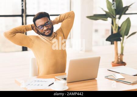 Happy afro manager stretching hands at work Stock Photo