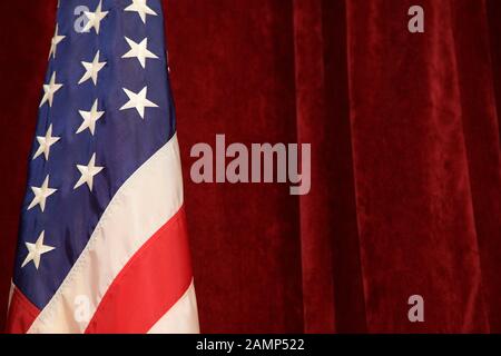 The American Flag pictured in front of red velvet curtains. Stock Photo