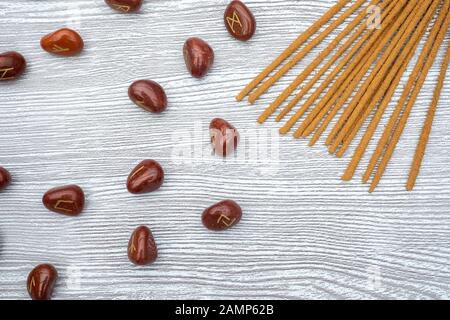 Flat lay composition of rune stones, dried white sage, incense and Tibetan singing bowls on a wooden background Stock Photo