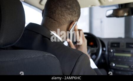 Afro-American man calling on phone from car, stressful day of businessman Stock Photo