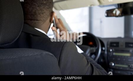 African-American man communicating by smartphone while driving car, back view Stock Photo