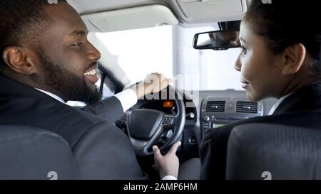 Two multi-ethnic colleagues flirting, discussing business in car, having affair Stock Photo