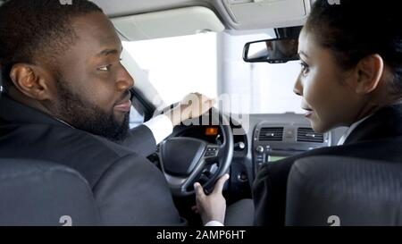 Mixed-race colleagues looking at each other, flirting sitting in parked car Stock Photo