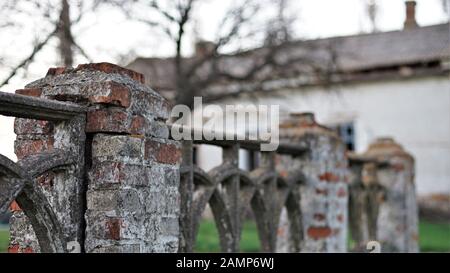 Old stone fence, in the background of an abandoned house Stock Photo