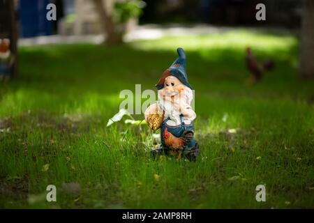 Garden gnome with a rooster on the lawn Stock Photo