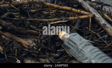 Empty plastic bottle thrown by storm lying on seashore water and shore pollution Stock Photo