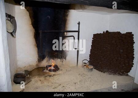 An open fireplace in a traditional old-fashioned Irish cottage. A stack of turf can be seen on the right of the photo. Stock Photo