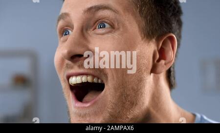 Excited man watching sports game on TV, supporting team, extreme happiness Stock Photo