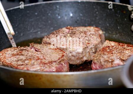 Cooking seasoned fillet beef steak in a frying pan. Stock Photo