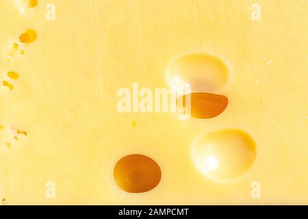 Emmental cheese texture close up. Macro Swiss yellow cheese with holes background Stock Photo