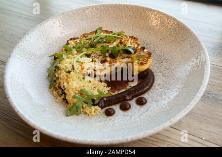 Vegetarian restaurant dish of grilled cauliflower with couscous. Stock Photo