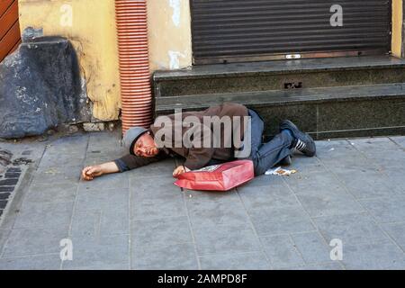 Lviv, Ukraine - 26 October 2019: Drunken homeless man sleeping on city street near shop staircase Stock Photo