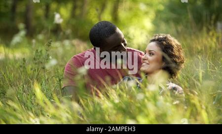 Couple in love spending weekends together sitting in high grass at park, outdoor Stock Photo