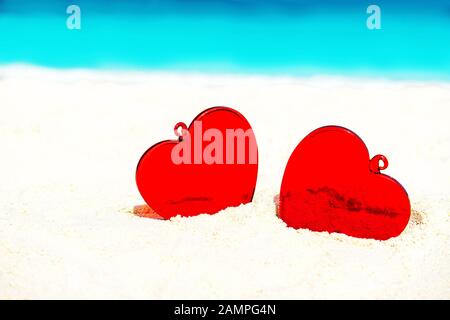 Red hearts on white yellow sand beach. Love concept for Valentine's Day or summer tropical vacation. Stock Photo