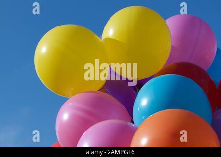 Multi-coloured party balloons pictured against a blue sky. Stock Photo